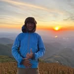 Alan Rafael Laurindo de blusa azul em uma paisagem de montanha ao amanhecer