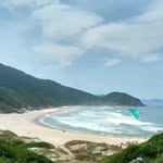 Praia cercada por vegetação no acervo de viagens do Alan